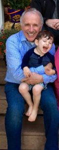 Grandpa in blue dress shirt holding laughing Grandson on his lap