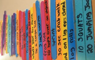 Kids Christian Fitness Workout Sticks. Multicolored popsicle sticks with different workout movements written on them in black marker.