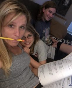 Meet Jan Tiffany tutoring two girls on the couch with a pencil in her mouth.