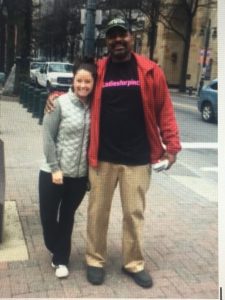 Girl in silver vest standing with street pastor in black tshirt and red coat in uptown charlotte