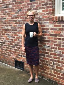 Inspirational Fitness Testimony from a Charlotte Leader, woman in black dress holding a cup of coffee in front of a brick building