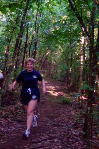 Retired CMPD Officer Becomes Fitness Coach, woman running on a trail in blue CMPD fitness outift