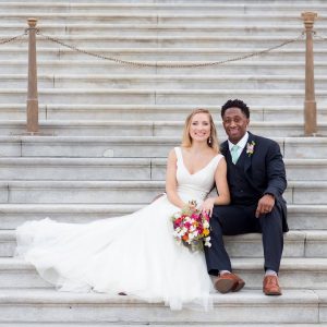 This is a super fit Christian leader you MUST get to know, husband and wife sitting on the church stairs on their wedding day.