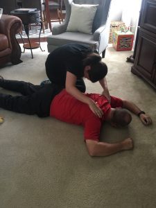 Today's Spotlight Athlete, Pastor Brent Watts, wife in black tshirt giving husband in red tshirt a back massage after a hard workout on the floor
