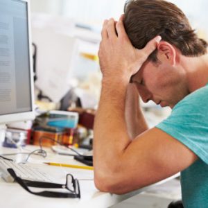 Is stress affecting your physical health, man at a desk with his head in his hands looking stressed out