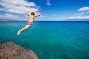 Workout Wednesday - Man jumping off cliff into the ocean. Summer fun lifestyle.