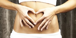 picture of a womans hands on her stomach in the shape of a heart around her belly button