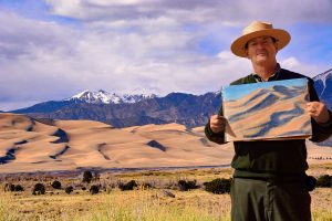 Park Ranger Patrick posing with a sketch of the Dunes at Great Dunes in Colorado. One stop during Week 4 of MissionFiT's Challenge the National Parks!